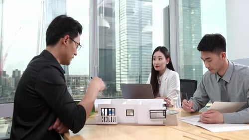 Architects Reviewing Plans and Model in Modern Office