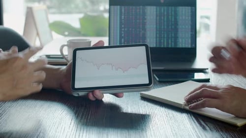 Brokers Analyzing Stock Market on Chart on Tablet Computer