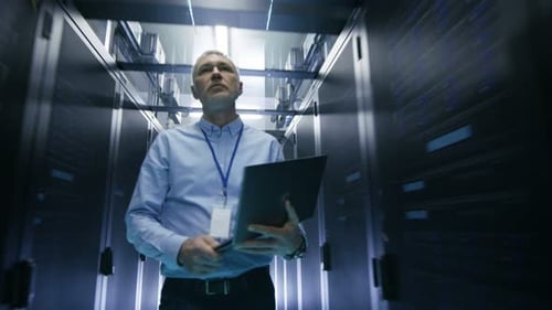 Im Rechenzentrum geht ein Serveringenieur durch das Rechenzentrum mit Reihen von Server-Racks, während er La hält
