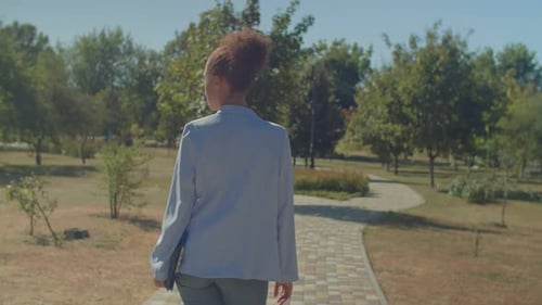 Woman Walking in Park Holding Portfolio