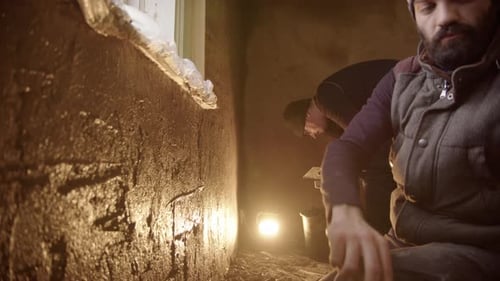 Adults Plastering Interior Wall in Dimly Lit Room