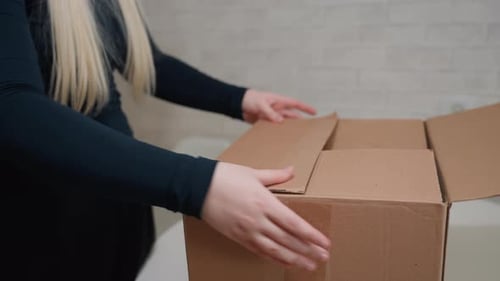 Woman Closing and Carrying a Cardboard Box Indoors