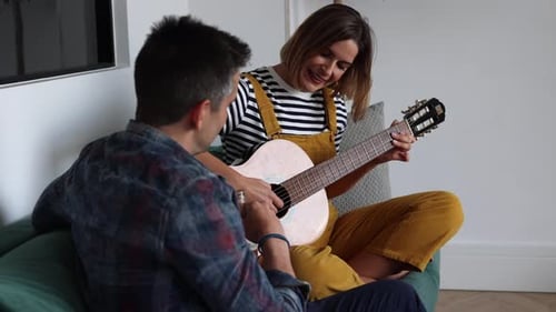 Woman Playing Guitar with Friend in Cozy Home