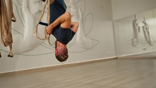 Man Practicing Aerial Yoga Inversion in Studio