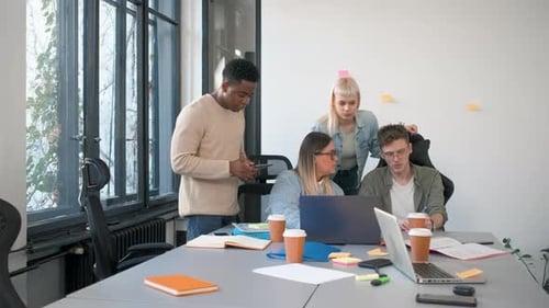 Diverse group of young people working on new project together in office.