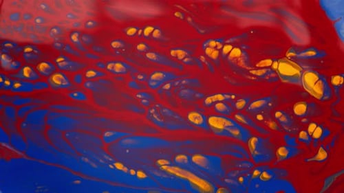 Abstract pattern of blue, red and orange liquid paint in macro