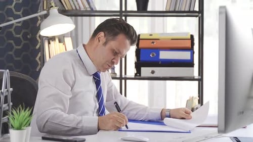 Office worker signs paperwork and necessary documents with pen.