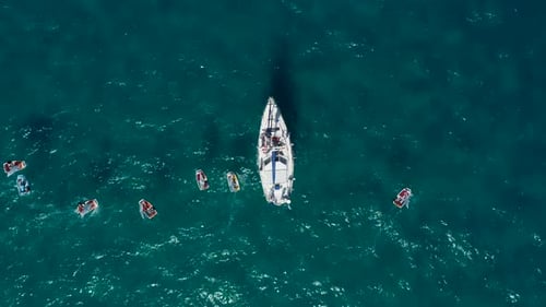 Yacht blanc ancré en mer avec de petits voiliers.