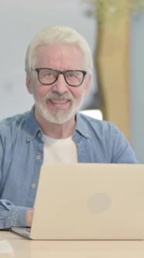 Senior Man Smiling in Front of Laptop