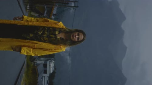 Woman in Yellow Raincoat Gazing up in Urban Setting