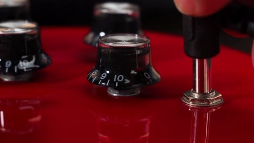 Close-up of a man attaching a jack to an electric guitar.