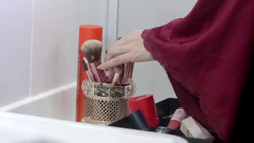 Woman Taking a Makeup Brush from Holder