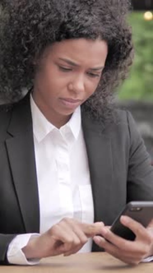 African Woman Using Smartphone Sitting in Outdoor Cafe, Vertical Video