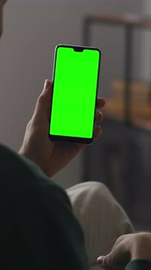Person Holding Modern Smartphone with Bright Green Chroma Key Screen Indoors Showcasing Blank Mobile