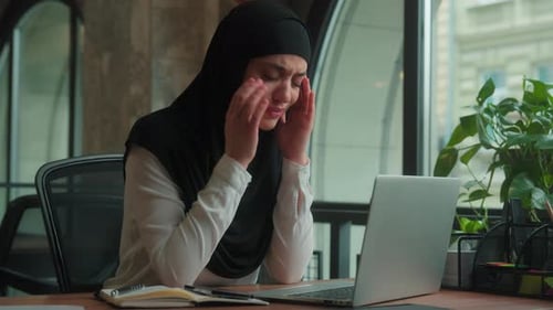Woman Massaging Temples in Office with Laptop