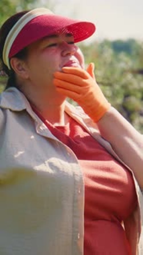 Joyful Woman Wearing a Sun Visor Expressing Emotions While Enjoying a Sunny Day Outdoors Surrounded
