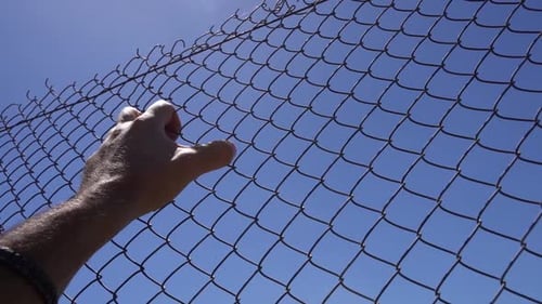 Hand on an Iron Fence Against the Sky