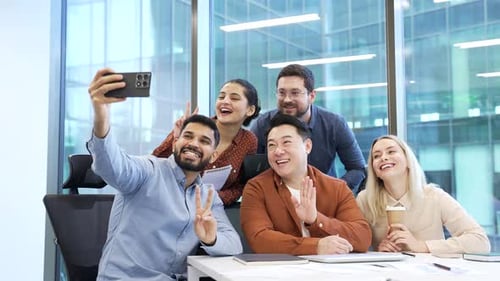 Group of happy business people taking selfie using mobile phone at workplace in business office.
