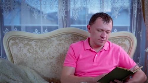 Adult Reading Book on Sofa at Home