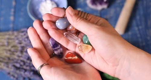 Mulher com pedras preciosas de chakra na mesa de madeira azul, closeup
