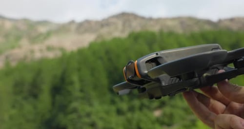 DJI avata held by hand showing to camera in front of forest background