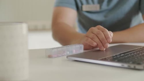 Man Types on Laptop with Medicine Nearby