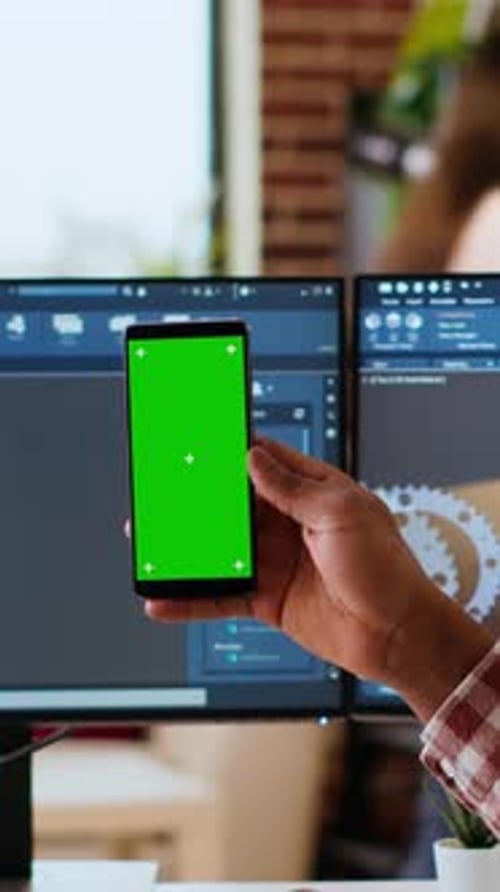 Vertical Video Software Developer Creates a Gear Prototype on Dual Monitors Next to Chroma Key