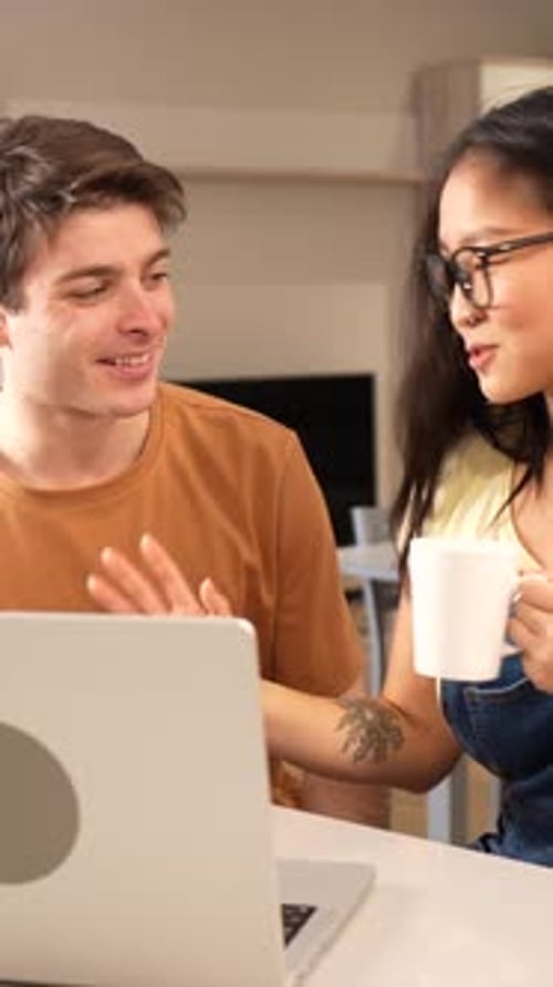 Young Couple Talking at Table with Laptop