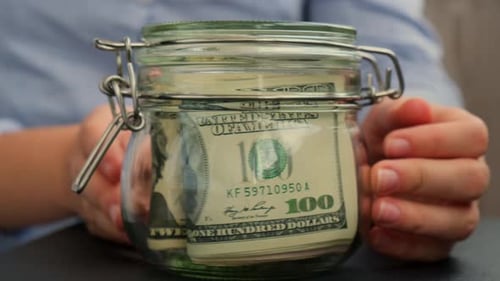 Unrecognizable Woman Turn Saving Money In Glass Jar Filled with Dollars Banknotes TRAVEL