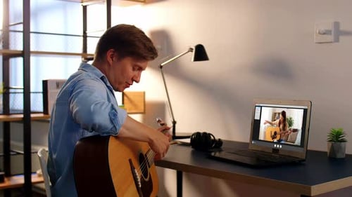 Man taking guitar lesson online from home