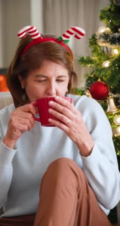 Festive Woman Drinking Coffee by Christmas Tree