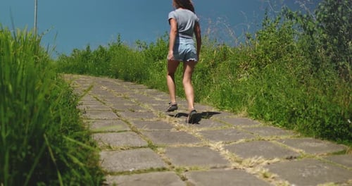 Woman Walking Along Path By Tall Grass