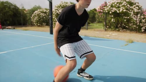 Teen Dribbles Basketball on an Outdoor Court