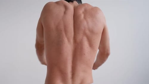 Muscular Adult Man Stretching Back Muscles Indoors