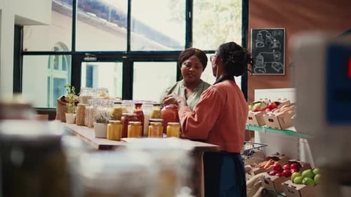 Women Discussing Jarred Goods in Urban Market Setting