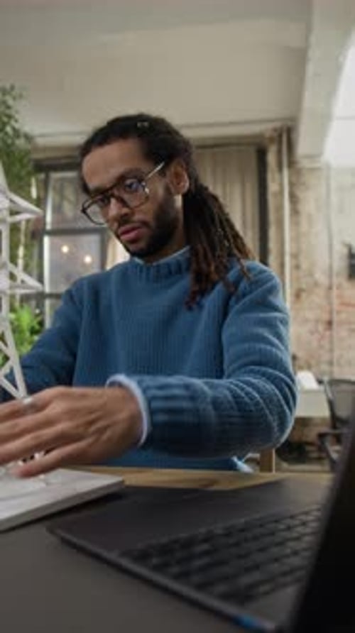 Biracial Male Engineer Adjusting Electric Tower Model at Office Desk