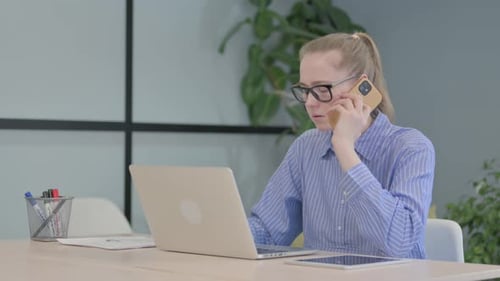Woman Talking on Phone While Using Laptop