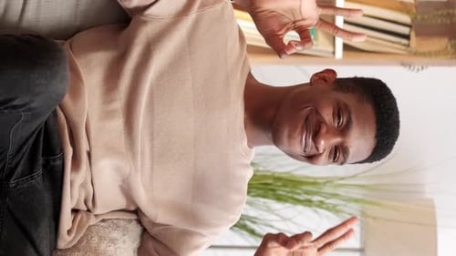 Cheerful Man Sitting on Couch Makes Hand Gestures