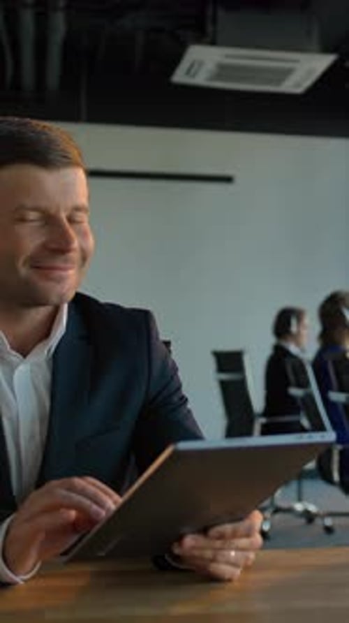 Vertical of Smiling Handsome Boss Enterpreneur with Tablet PC with Call Center