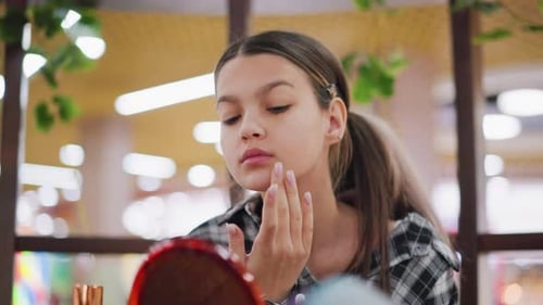 Teenager Applies Lotion to Face in Mirror