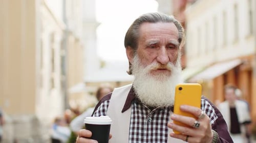 Senior Man Using Phone with Coffee in City