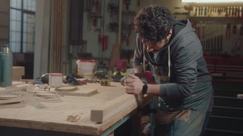 Woodworker Smoothing Wood Plank with Plane in Workshop