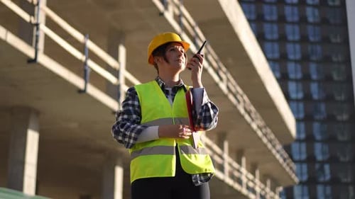 Female Engineer Directing Construction Using Walkie-Talkie