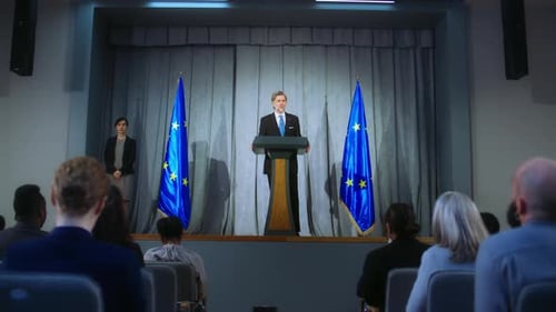 Official Giving Speech in Front of EU Flags
