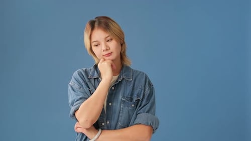 Young woman shows gesture I don't know looking at camera isolated on blue background