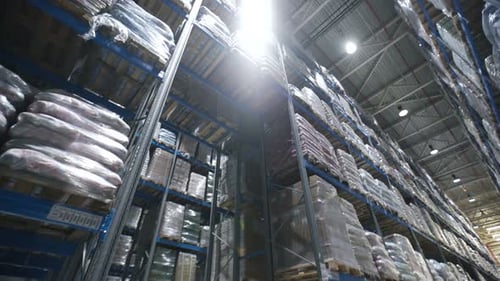 Inside large factory warehouse aisles with forklift moving boxes and goods