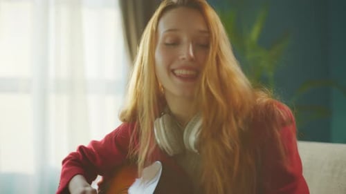 Woman Plays Guitar and Sings in Living Room
