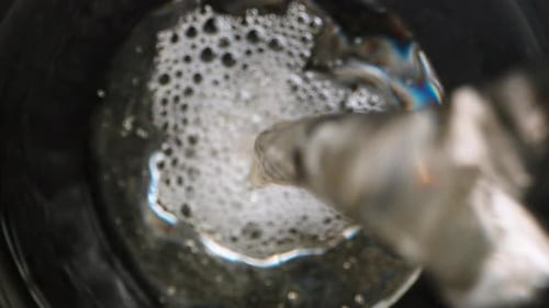 I pour wine from a blue bottle, the camera is inside the glass, top view. Dolly slider extreme close