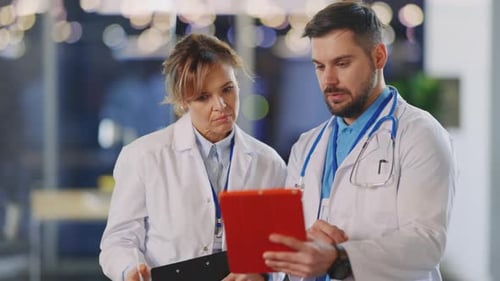 Caucasian Doctor and Young Nurse Cooperating in Hospital Office Two Healthcare Professional Workers