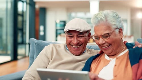 Happy Senior Couple Laughing Together with a Tablet